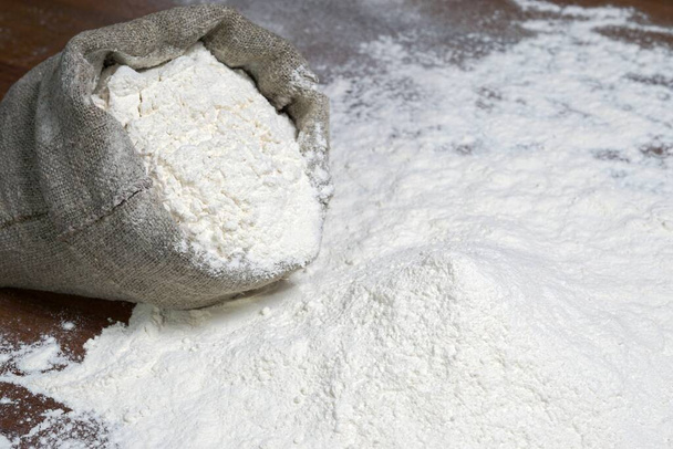 A pile of flour on a dark table. Spilled flour. Flour texture - Photo, Image