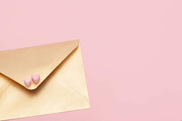 Golden paper envelope with two hearts from marshmallow isolated on pink background - Фото, зображення