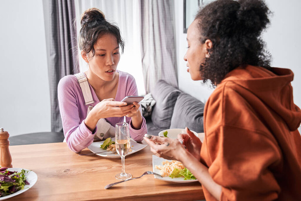Chicas discutiendo algo en los teléfonos inteligentes en la cocina - Foto, Imagen