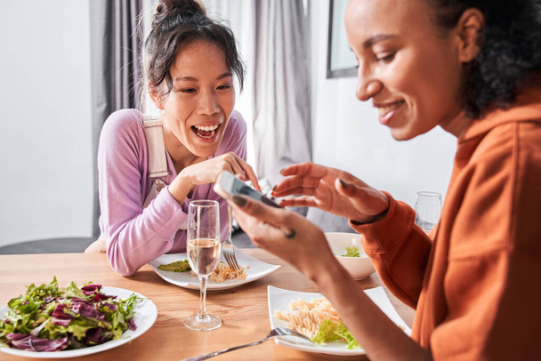 Girls laughing while looking at smartphone during dinner - Fotoğraf, Görsel