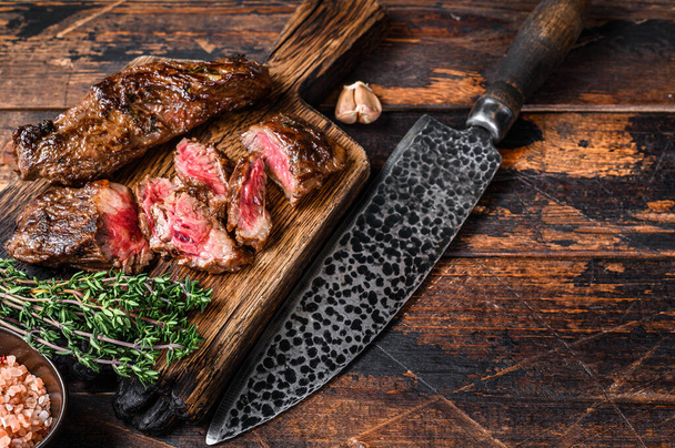 Grilled bbq skirt steaks slices on a wooden board. Dark wooden background. Top view. Copy space. - Photo, Image