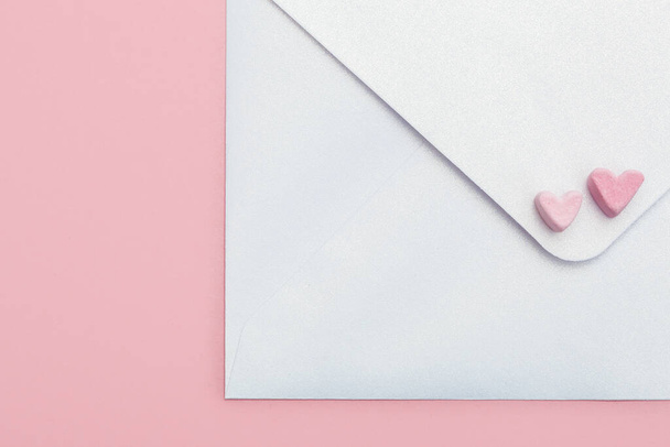 light mother-of-pearl paper craft envelope with two hearts from marshmallow isolated on pink background - Foto, afbeelding