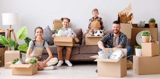 glückliche Familienmutter, Vater und Kinder ziehen in eine neue Wohnung und schauen beim Auspacken in die Kamera - Foto, Bild