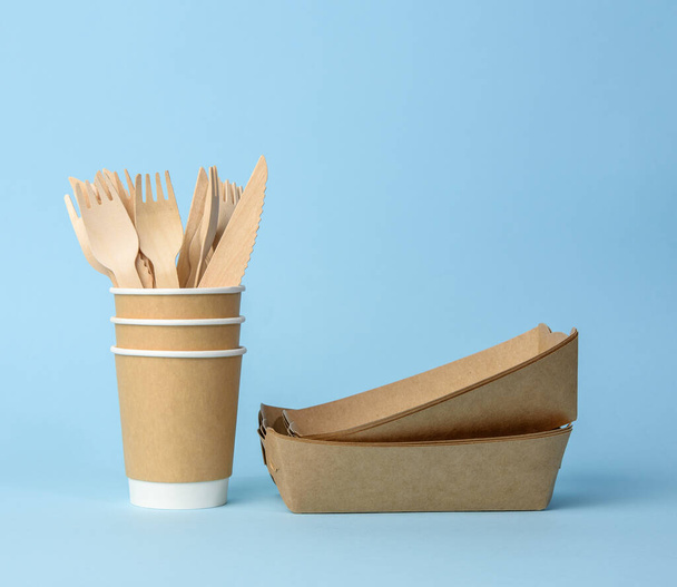 brown paper cup, plates on a blue background. Plastic rejection concept, zero waste - Фото, изображение