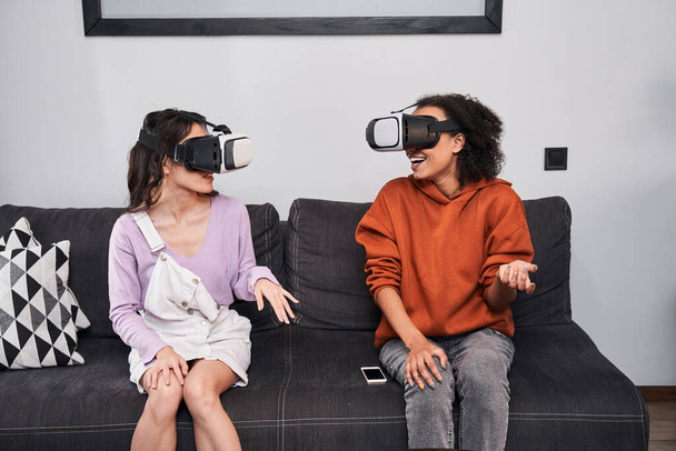 Besties sitting at sofa and using virtual reality headset - Foto, Imagen