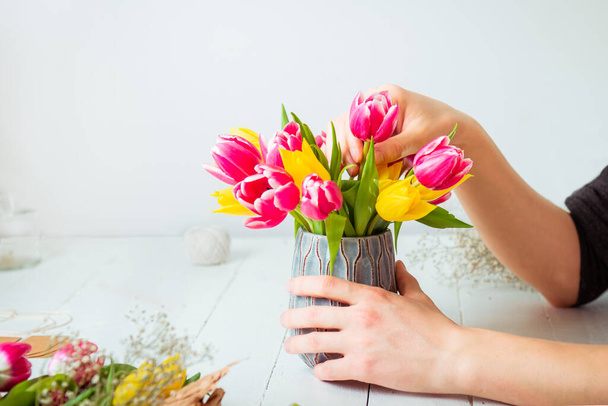 No face young man making spring bouquet using tulips. Online self-education of floristry. Learning flower arranging. Flowers delivery. Male florist creating order. Selective focus. - Foto, imagen