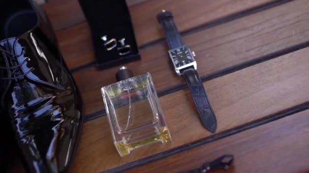 Gelakte herenschoenen, polshorloge, parfum en manchetknopen op houten backgroun. close-up - Video