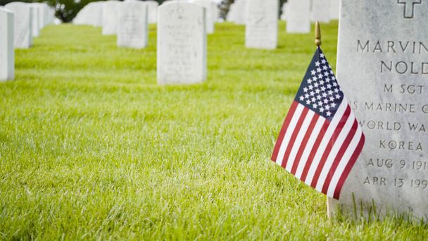 Денвер, штат Колорадо, США - 26 мая 2019 года - маленькие американские флаги рядом с белыми мраморными плитами на национальном кладбище Форт-Логан в День памяти. - Фото, изображение