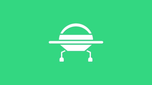 Fehér UFO repülő űrhajó ikon elszigetelt zöld alapon. Repülő csészealj. Idegen űrhajó. Futurisztikus ismeretlen repülő tárgy. 4K Videó mozgás grafikus animáció - Felvétel, videó