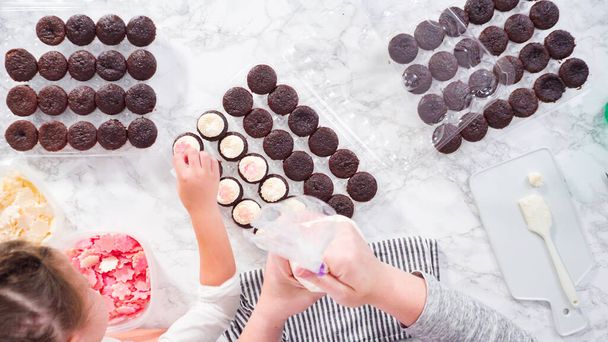 Plat gelegd. Stap voor stap. Piping Italiaanse boterroom glazuur op de top van mini chocolade cupcakes. - Foto, afbeelding