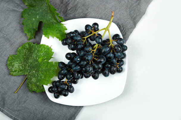 Куча красного винограда в белой тарелке - Фото, изображение