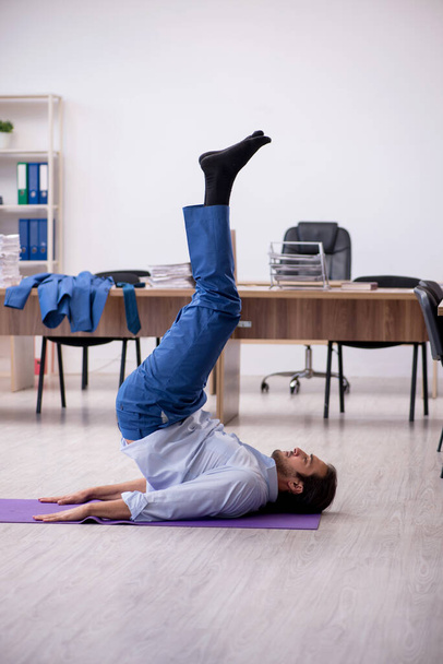 Молодой работник делает спортивные упражнения во время перерыва - Фото, изображение