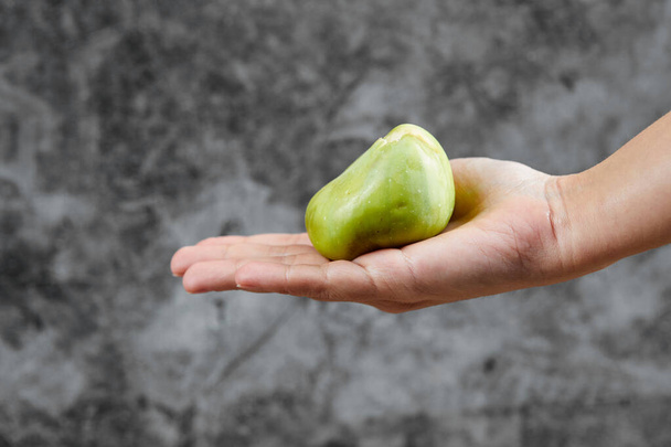 Hand holding a fig on a marble background - Foto, afbeelding