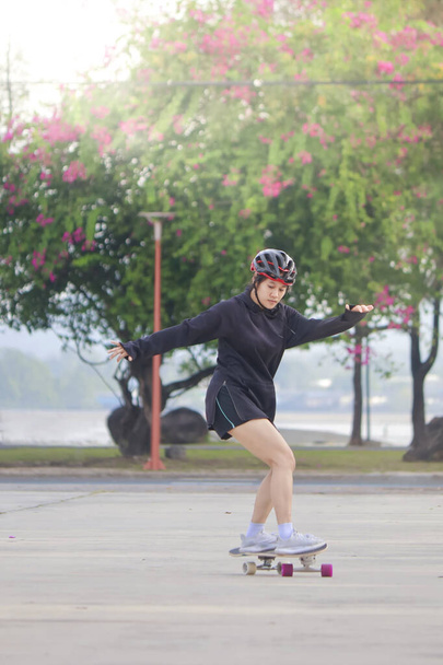 Mulheres asiáticas em skates embarcam ao ar livre no belo dia de verão. Jovens felizes jogam surfskate no parque na hora da manhã. Esporte conceito de estilo de vida atividade - Foto, Imagem
