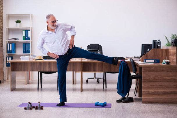 Ein alter Geschäftsmann macht Sport im Büro - Foto, Bild
