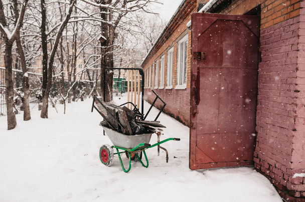 narzędzia do usuwania śniegu są ładowane do wózka ręcznego do transportu na podwórku w silnych opadach śniegu - Zdjęcie, obraz