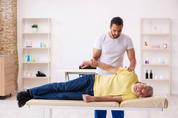 Alt männlich patient besuch jung männlich arzt chiropraktiker - Foto, Bild