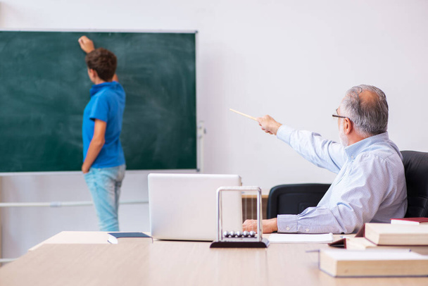 Öreg férfi tanár és iskolás fiú az osztályteremben - Fotó, kép
