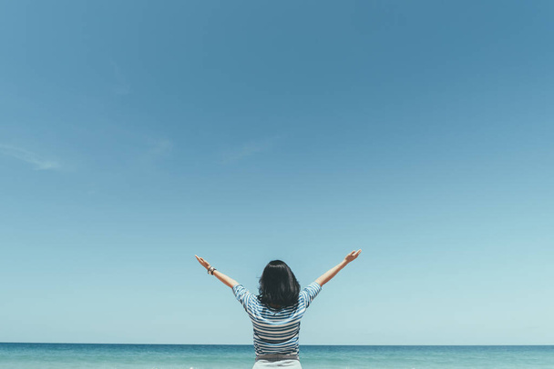 青い空を背景に熱帯のビーチで手を挙げてくれる幸せな女性。旅行休暇と自由は良い概念を感じる。ヴィンテージトーンフィルターエフェクトカラースタイル. - 写真・画像