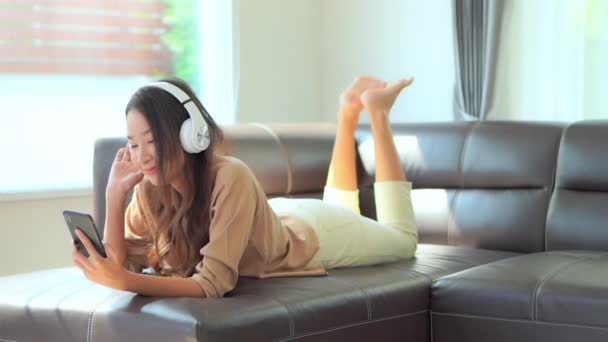 filmati di bella giovane donna asiatica che ascolta musica con smartphone e cuffie - Filmati, video
