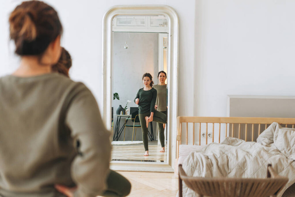 Attraktive Mutter mittleren Alters Frau und Tochter Teenager ptactice Yoga zusammen im hellen Raum - Foto, Bild