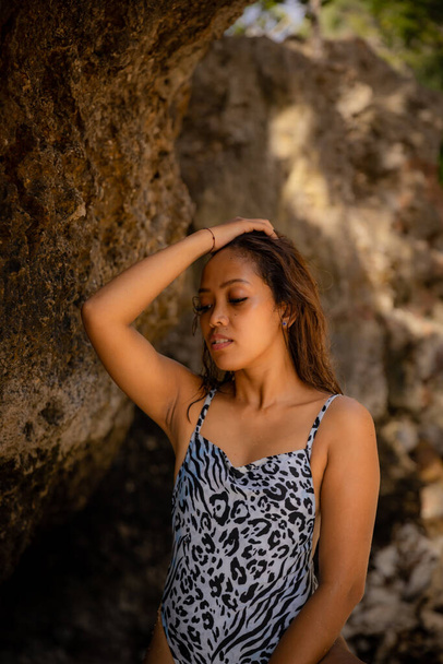 Retrato de bela mulher asiática vestindo maiô. Mulher sexy em pé perto da rocha na praia. Pele bronzeada. Férias de verão na ilha tropical. Estilo de vida de viagem. Padang Padang, Bali, Indonésia - Foto, Imagem