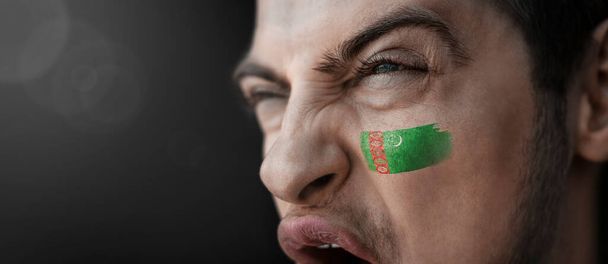 Un hombre gritando con la imagen de la bandera nacional de Turkmenistán en su cara - Foto, Imagen