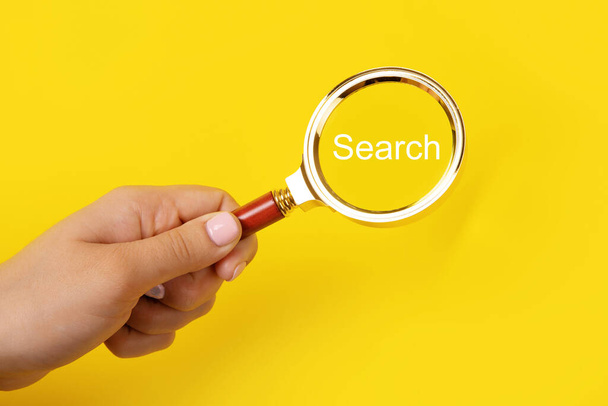 magnifier in hand with inscription search over  yellow background, search concept - Photo, Image
