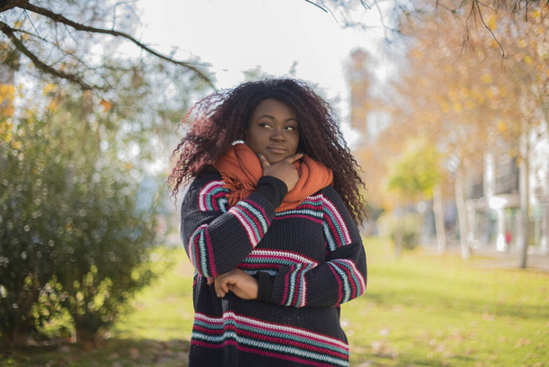 fiatal gyönyörű afro-amerikai nő visel színes pulóver gyanús őszi parkban    - Fotó, kép