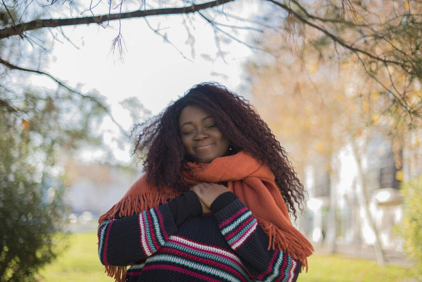 young beautiful  African American woman wearing colorful sweater  closing eyes   in autumn  park    - Photo, Image