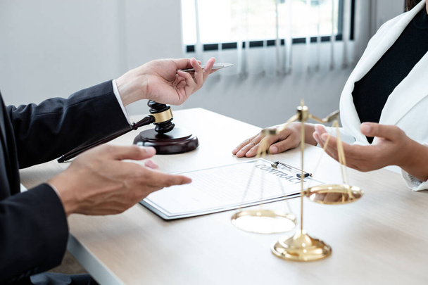 A male lawyer or a judge counseling clients about judicial justice and prosecution with scales, judges gavel, legal documents legal services concept. - 写真・画像