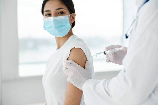 Tıbbi maskeli kadın hasta ve enfeksiyona karşı şırınga aşısı. - Fotoğraf, Görsel