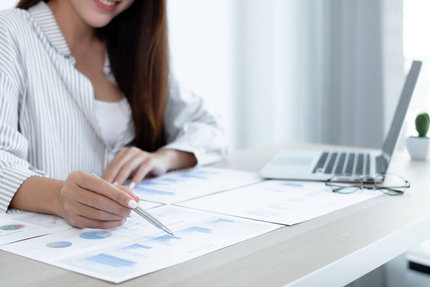 Asiatique femme comptable assis à leur bureau et calcule des graphiques financiers montrant les résultats de leurs investissements, planifier un processus de croissance d'entreprise réussie. - Photo, image