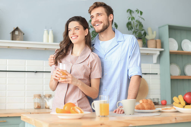 Beautiful couple hugging each other and looking away in kitchen in the morning - Photo, image