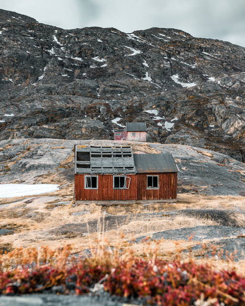 A vertical shot of old wooden houses on the top of the rock - Ghost village in Greenland, Assaqutaq - Fotoğraf, Görsel