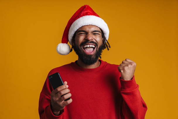 Excited african american guy using cellphone and making winner gesture isolated over yellow background - Φωτογραφία, εικόνα