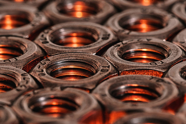 A closeup shot of metal screw nuts with golden lights coming under it - Foto, Imagen
