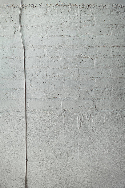 A vertical shot of a white concrete wall with a wire on it - Photo, Image