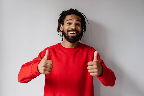 Joyful african american man smiling and showing thumbs up at camera isolated over white background - Foto, imagen