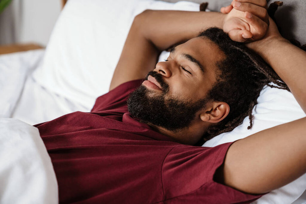 Tired young african-american man sleeping in bed - Φωτογραφία, εικόνα