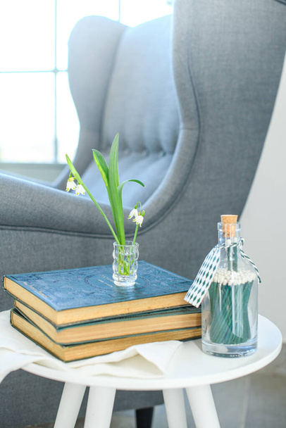 Вертикальний знімок зручного синього крісла біля маленького столу з книгами в кутку будинку
 - Фото, зображення