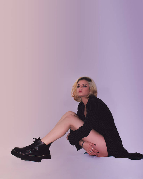 A posing a stylish, attractive blonde female in a beautiful black outfit on the purple background - Φωτογραφία, εικόνα