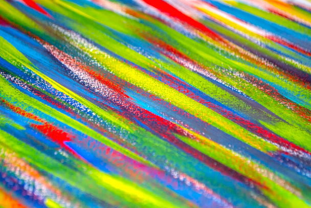 Background from different strokes of red, yellow, green and blue paint with brush close-up. Bright colorful backdrop of colored brush lines. Mixing color streaks of paint with cracked and scratched. - Photo, Image