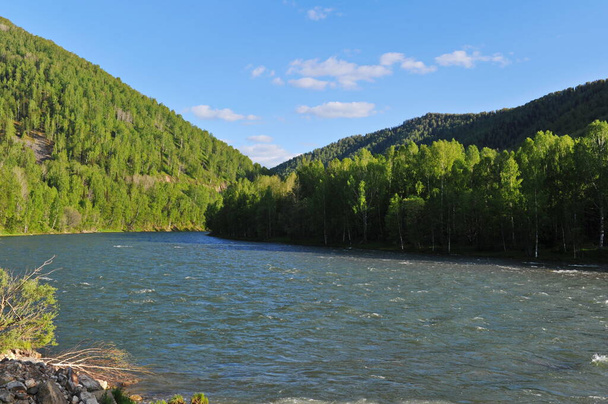 Ridder, Kazachstan - 06.05.2013: De Irtysh River, die stroomt langs een bergachtig en heuvelachtig gebied met verschillende vegetatie. - Foto, afbeelding
