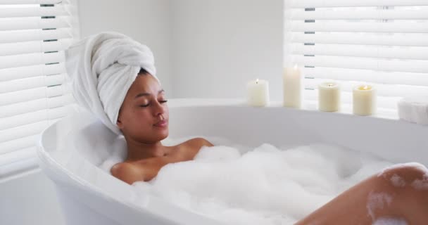 African american woman relaxing in the bath tub in the bathroom at home - Materiaali, video