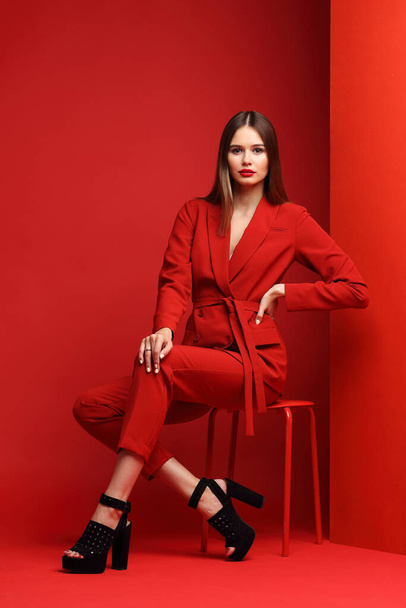 Fashion young woman in red suit. Red background. - Фото, зображення