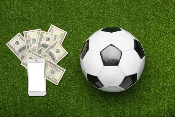Χρήματα, κινητό τηλέφωνο και μπάλα ποδοσφαίρου στο φόντο χρώμα. Έννοια του στοιχήματος αθλητισμού - Φωτογραφία, εικόνα