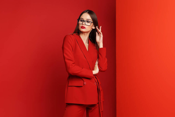 Fashion young woman in red suit. Red background. - Foto, immagini