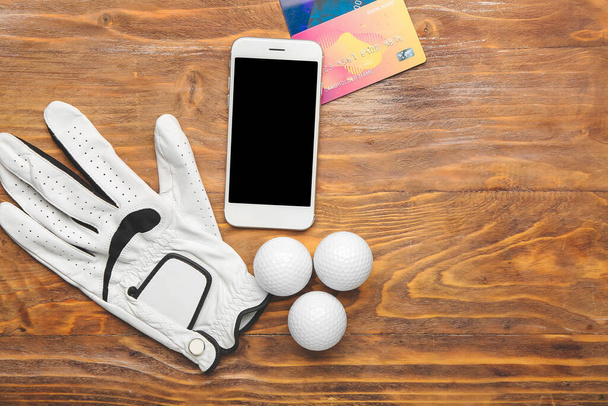 Luva de golfe, telefone celular e cartões de crédito em fundo de madeira. Conceito de aposta desportiva - Foto, Imagem