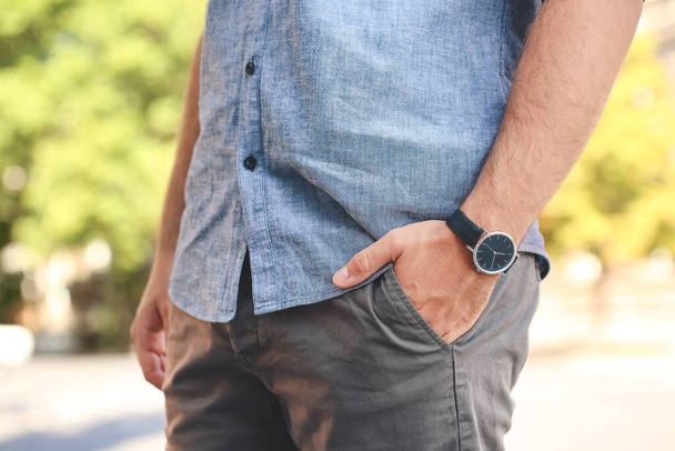 Νεαρός άνδρας με κομψό ρολόι χειρός σε εξωτερικούς χώρους - Φωτογραφία, εικόνα